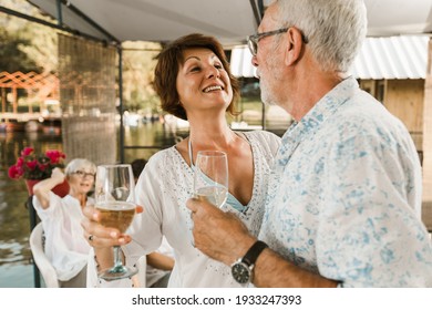 Senior Couple Dancing On A Party Outside Drinking Wine.