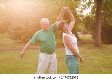 Senior couple dancing in park on sunny day