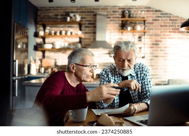 Senior couple doing bills and payments together in the kitchen at home - Powered by Shutterstock