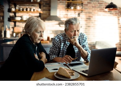 Senior couple doing bills and payments together in the kitchen at home - Powered by Shutterstock