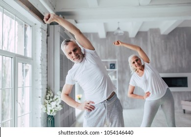 Senior Couple Is Doing Fitness Training At Home. Doing Yoga Together. Healthy Lifestyle Concept.