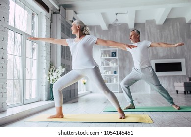 Senior Couple Is Doing Fitness Training At Home. Doing Yoga Together. Healthy Lifestyle Concept.