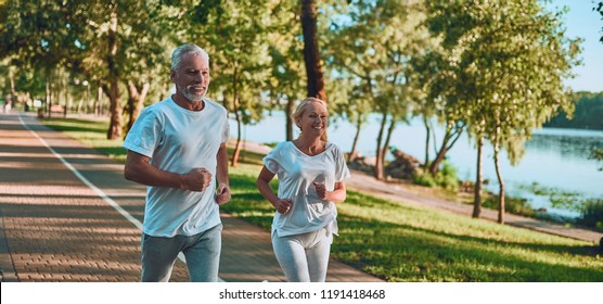 Senior couple is doing sport outdoors. Running in park in the morning. - Shutterstock ID 1191418468