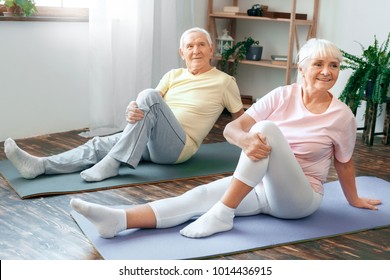 Senior couple doing yoga together at home health care leg stretching