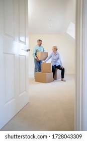 Senior Couple Downsizing In Retirement Carrying Boxes Into New Home On Moving Day