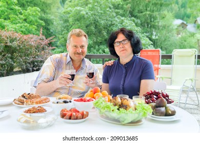 The senior couple drink red wine on terrace in sunny day - Powered by Shutterstock