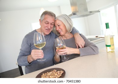 Senior Couple Drinking Wine In Home Kitchen