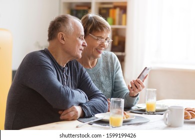 Senior couple eating breakfast and using smartphone at home
 - Shutterstock ID 1599199426