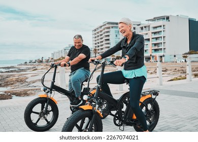 Senior couple, electric bike and smile by the beach for fun bonding cycling or travel together in the city. Happy elderly man and woman enjoying cruise on electrical bicycle for trip in Cape Town - Powered by Shutterstock