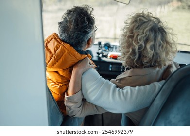 Senior couple embraces in a camper van, enjoying a road trip and scenic views, exemplifying love and freedom in retirement - Powered by Shutterstock