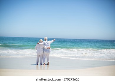 Senior couple embracing and pointing at the beach - Powered by Shutterstock