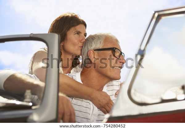 Senior couple embracing in\
sports car