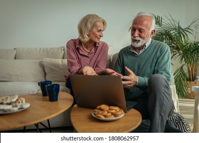 Senior Couple Enjoying In The Comfort Of The Living Room And Using Laptop