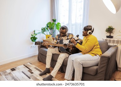 Senior couple enjoying music at home, with the man playing guitar and the woman singing into a microphone. - Powered by Shutterstock