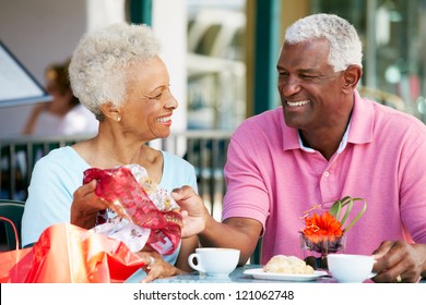 Senior Couple Enjoying Snack At Outdoor Cafe After Shopping - Powered by Shutterstock