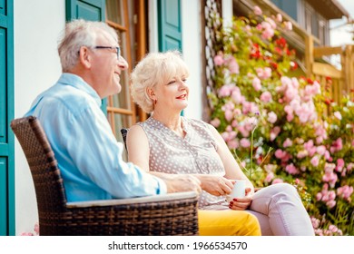 Senior couple enjoying their coffee on porch in front of their house - Powered by Shutterstock