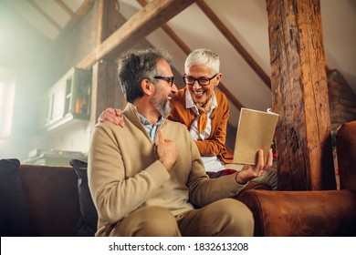 Senior couple enjoying together in the comfort of the living room and reading a book