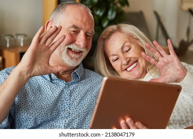 Senior Couple Enjoying Zoom Video Chat With Family On Tablet Computer At Home