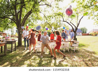 A Senior Couple And Family Dancing On A Garden Party Outside In The Backyard.