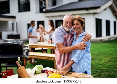 Senior couple with family outdoors on garden barbecue, grilling. - Powered by Shutterstock