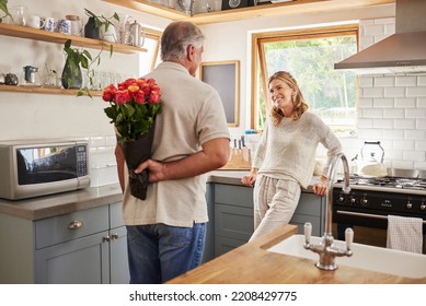 Senior, couple and flowers for love in kitchen, husband with bouquet of roses to wow wife, happy and marriage on wedding anniversary. Man, flowers and woman together, romance and surprise in home - Powered by Shutterstock