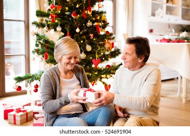 Senior couple in front of Christmas tree with presents. - Powered by Shutterstock