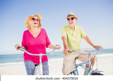 Senior Couple Going For A Bike Ride On The Beach