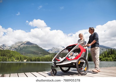 Senior Couple With Grandchildren In Jogging Stroller.