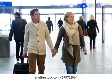 Senior couple in hallway of subway pulling trolley luggage. - Powered by Shutterstock