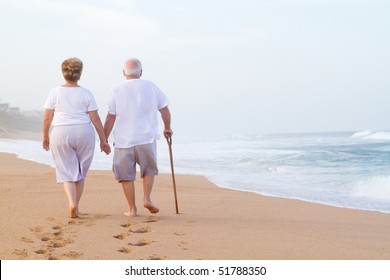 senior couple hand in hand walking on beach