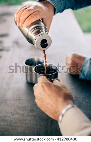 Senior Paar Hände gießen Kaffee aus der Thermoskanne.