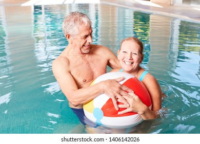 Senior couple has fun with a beach ball in the pool during a spa vacation - Powered by Shutterstock