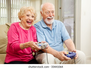 Senior couple has fun at home playing video games together.