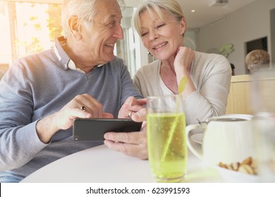 Senior couple having a drink in town and looking at smartphone