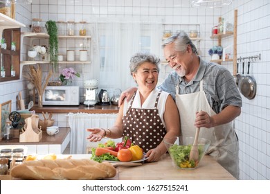 Senior couple having fun in kitchen with healthy food - Retired people cooking meal at home with man and woman preparing lunch with bio vegetables - Happy elderly concept with mature funny pensioner. - Shutterstock ID 1627515241
