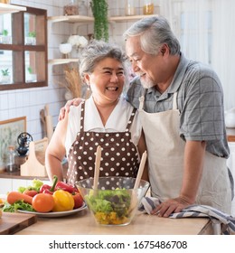 Senior Couple Having Fun In Kitchen With Healthy Food - Retired People Cooking Meal At Home With Man And Woman Preparing Lunch With Bio Vegetables - Happy Elderly Concept With Mature Funny Pensioner.