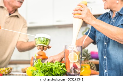 Senior Couple Having Fun In Kitchen With Healthy Food - Retired People Cooking At Home Preparing Blended Centrifuge Smoothie With Bio Fruit And Vegetable - Happy Elderly Concept With Mature Pensioner 