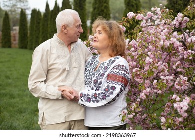 Senior Couple Having Fun In Summer Or Spring Nature Near Sakura Blooming Tree Wearing Ukrainian Embroidered Shirt