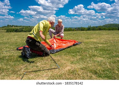 Senior couple having fun together while putting up a tent in nature with beautiful landscape in the background - Powered by Shutterstock