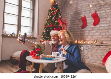 Senior couple having fun while having virtual party with friends and family on Christmas day; elderly couple having video call with children while celebrating Christmas - Powered by Shutterstock