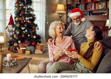 Senior couple having fun while surprising their adult daughter with a gift on Christmas day at home.  - Powered by Shutterstock