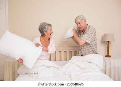 Senior couple having a pillow fight at home in the bedroom - Powered by Shutterstock