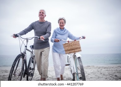 Senior Couple Having Ride With Their Bike On The Beach