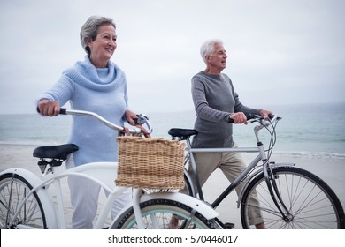 Senior Couple Having Ride With Their Bike On The Beach