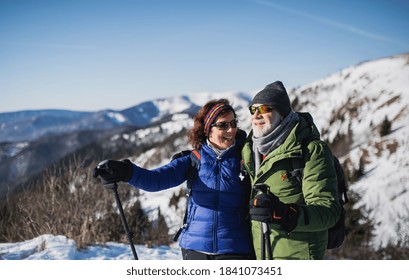 Senior couple hikers with nordic walking poles in snow-covered winter nature. - Powered by Shutterstock