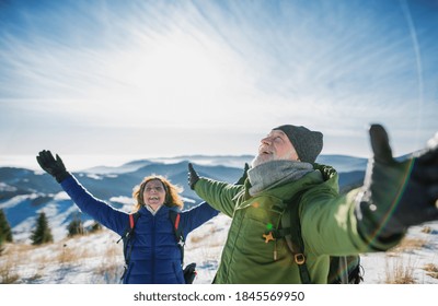 Senior couple hikers in snow-covered winter nature, stretching arms. - Powered by Shutterstock