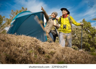 Senior couple of hikers spending a day on a mountain while woman is aiming at distance. - Powered by Shutterstock