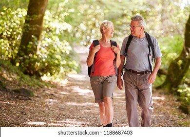 Senior Couple Hiking Along Woodland Path In Lake District UK Together