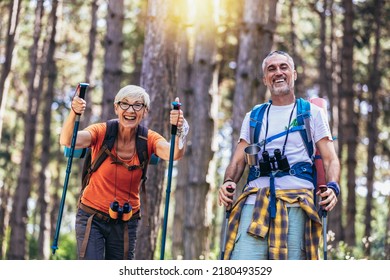 Senior couple hiking in forest wearing backpacks and hiking poles. Nordic walking, trekking. Healthy lifestyle. - Powered by Shutterstock