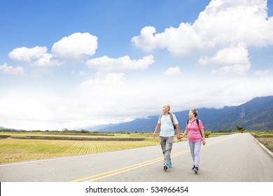 Senior Couple Hiking On The Country Road